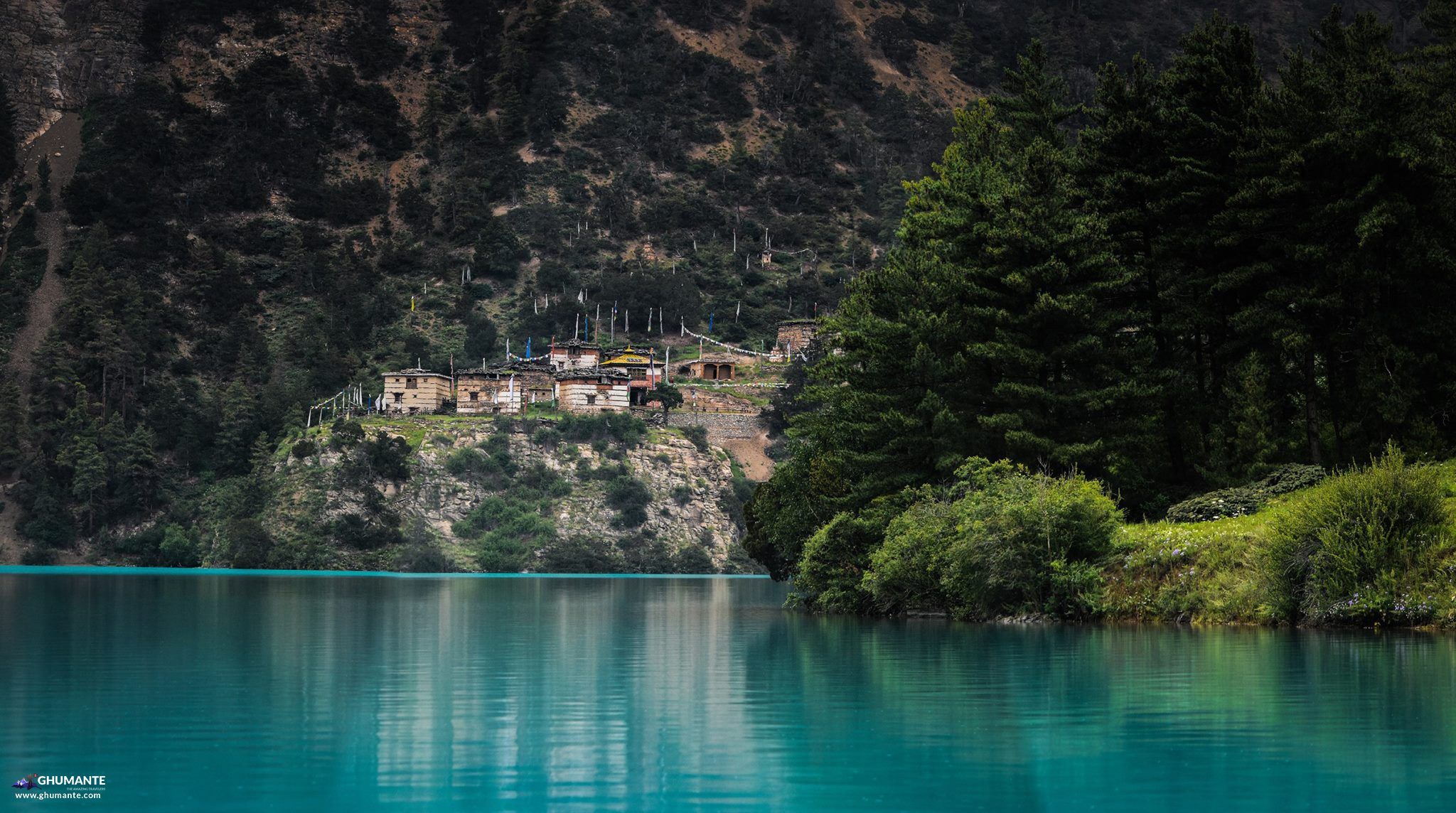 Stone monastery with prayer flags overlooking the lake